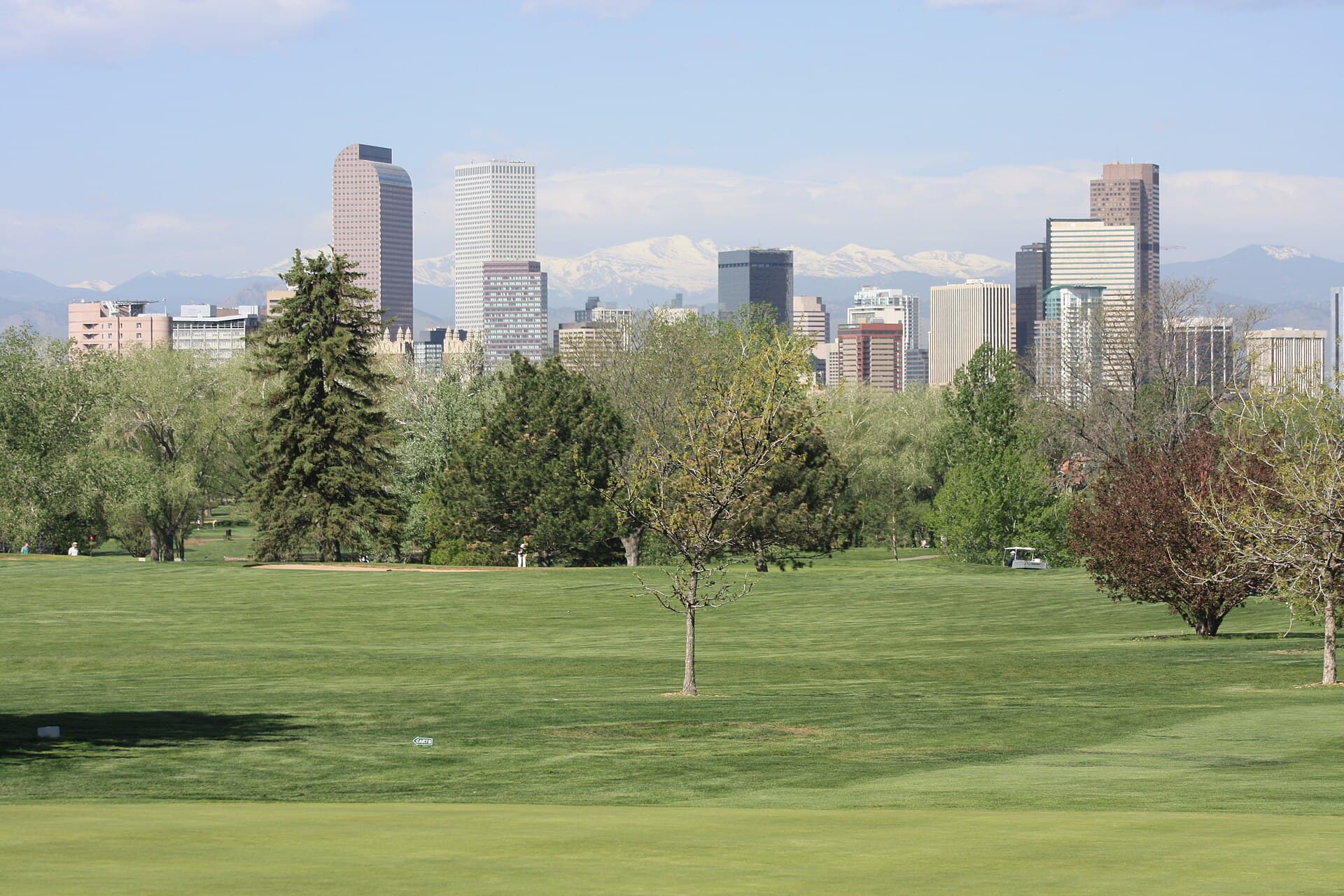 Downtown Denver skyline with snow-capped Mount Evans behind it, seen from City Park